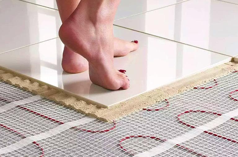 Electric underfloor heating mat being installed under floor tiles