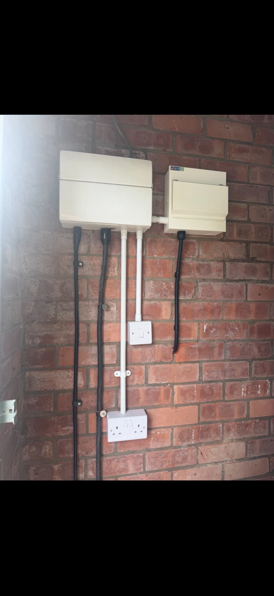 Consumer unit and EV isolator board with sockets installed on an outbuilding wall